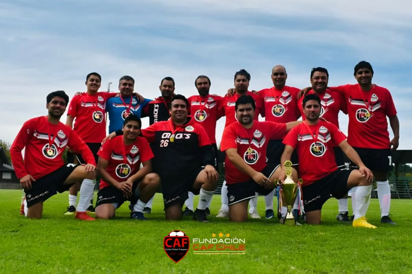 Equipo de fútbol adulto de camiseta roja posando en la cancha.