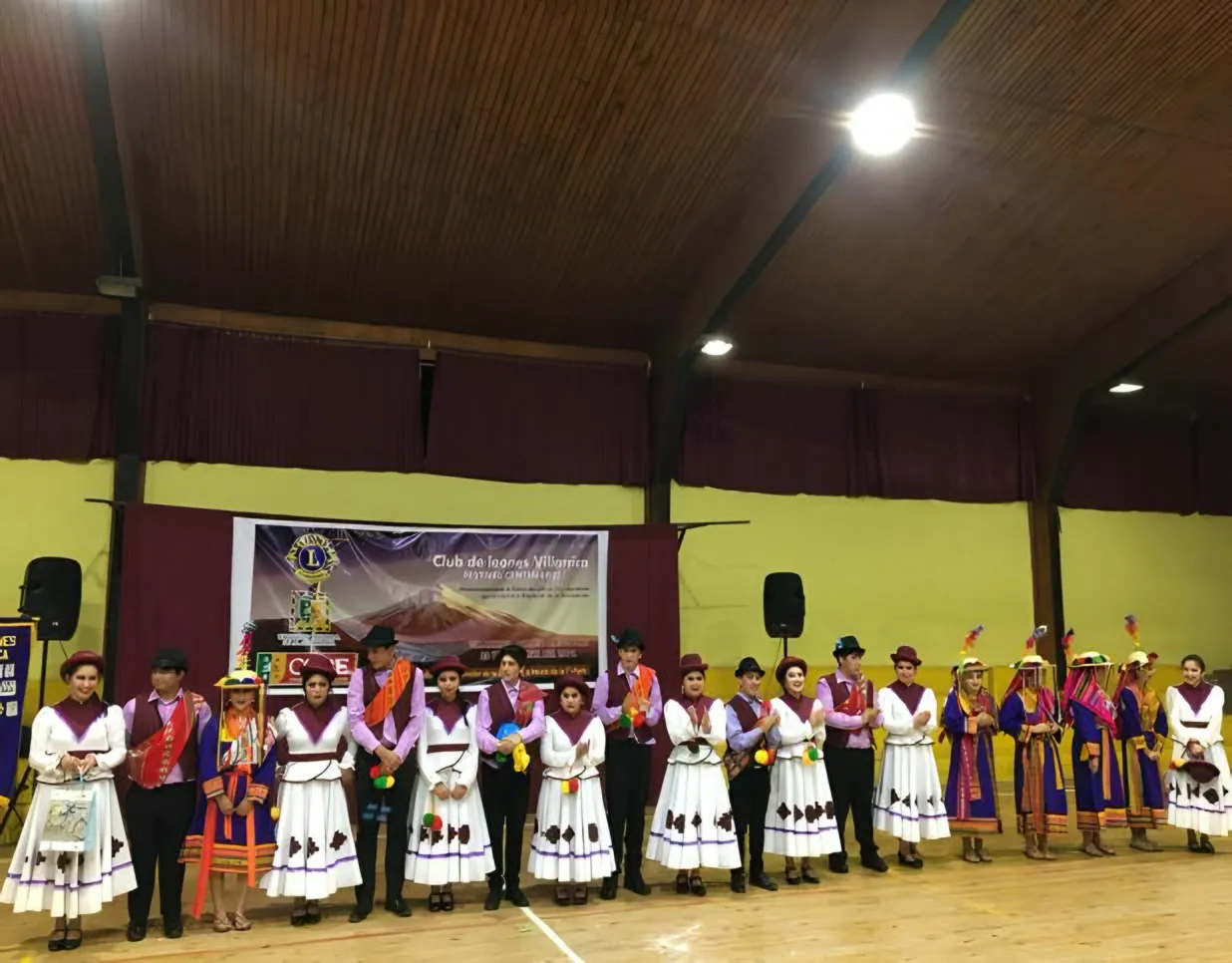 Conjunto folclórico formado en fila dentro de un gimnasio.